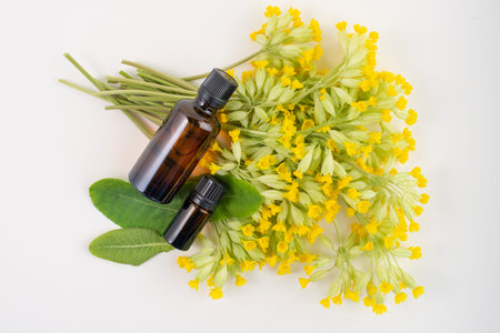 Dark glass bottles on cowslip, Primula veris, flowers, top view.