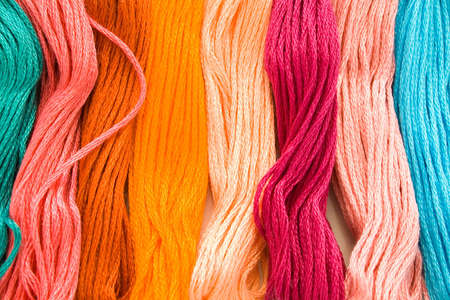 Eight skeins of different brightly colouredembroidery floss lying side by side.の写真素材