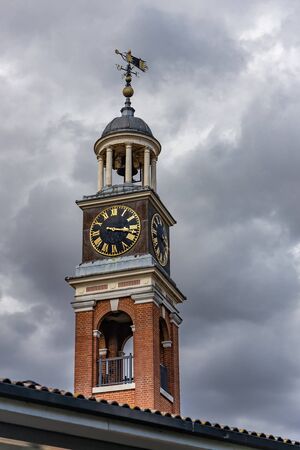 A clocktower and weathervane in front of stormy cloudsの写真素材