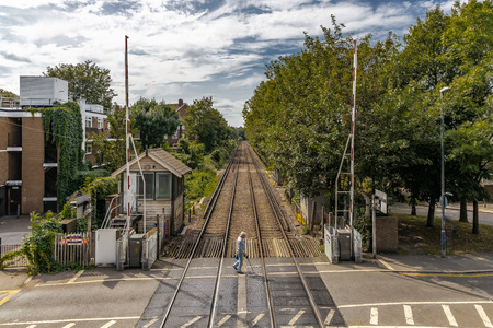 An old man with a walking stick cane crossing the train tracksのeditorial素材