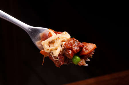 closeup on fork serving portion of meat with melted cheese, carrot peaの写真素材