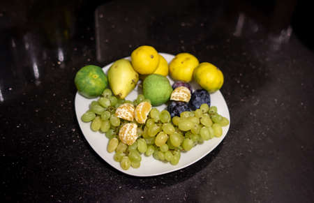 Green grape red plum green apple on plate on tableの写真素材