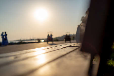 wooden sitting bench in the park and silhouettes of people with sunlightの写真素材
