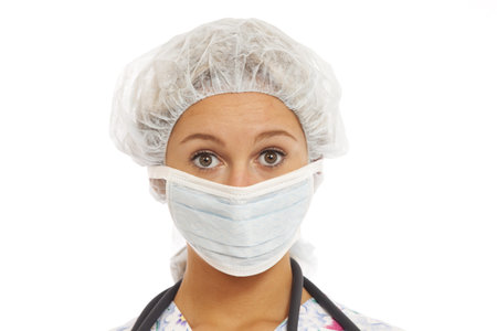 Portrait of young woman nurse in scrubs with mask and cap