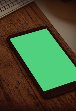 Smartphone with green screen on wooden table. view from above.の写真素材