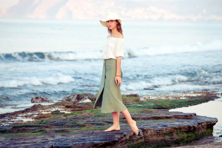 Young woman standing on the rock bear the seaの写真素材