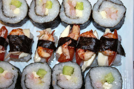 Cooking sushi rolls with nori seaweed sheets, rice sumesi, shrimp, cucumber, tuna, Philadelphia cheese and tomatoes on a bamboo mat Makisuの写真素材