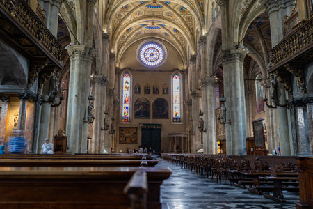Interior of a grand cathedral with soaring stone columns, stained-glass windows, and intricate vaulted ceilings. Rows of wooden pews line the space, creating a serene and sacred atmosphere.の写真素材