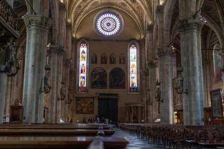 Interior of a grand cathedral with soaring stone columns, stained-glass windows, and intricate vaulted ceilings. Rows of wooden pews line the space, creating a serene and sacred atmosphere.の写真素材