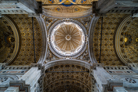 Intricate view of a cathedral's ornate dome ceiling with golden geometric patterns, decorative arches, and sculpted details, showing stunning architectural craftsmanship.の写真素材