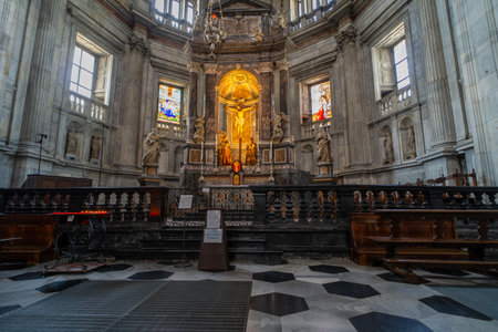 A beautifully ornate church altar with a golden crucifix centerpiece, surrounded by marble columns, statues of saints, and stained glass windows, creating a serene and spiritual atmosphere.の写真素材