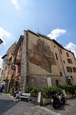 A historic mural painted on the side of a stone and stucco building in a European town, depicting a medieval map and artwork.の写真素材