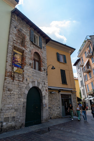 A historic stone building with a large arched green door and a religious mural on its wall, located in a narrow cobblestone street.の写真素材