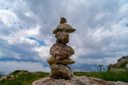 Stacked rocks balanced on a mountaintop with a cloudy sky in the background, symbolizing harmony, balance, and mindfulness in nature.の写真素材