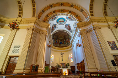 Interior view of a historic church showing intricate architectural details, grand columns, and ornate chandeliers. The altar features religious statues, candlesの写真素材