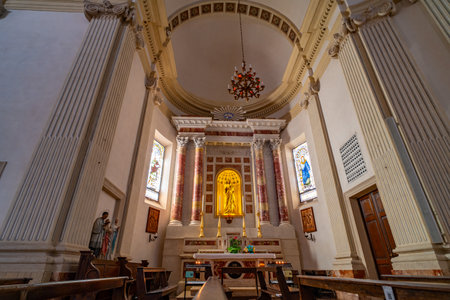 Interior view of a historic church showing intricate architectural details, grand columns, and ornate chandeliers. The altar features religious statues, candlesの写真素材