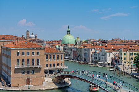 Scenic view of Venice, Italy, featuring the Grand Canal, a modern glass footbridge, and historic buildings with terracotta rooftops.の写真素材