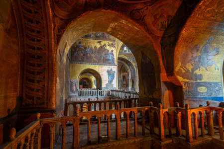 Golden mosaics and intricate frescoes adorn the interior of a historic basilica, showcasing religious art and marble columns under soft natural light.の写真素材