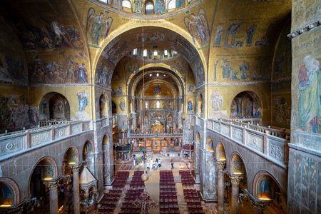 The ornate interior of St. Mark's Basilica in Venice, Italy, features golden mosaics, arched columns, and intricate religious artwork. A stunning example of Byzantine architecture.の写真素材