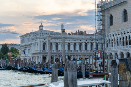 Scenic view of Doge's Palace and Biblioteca Nazionale Marciana with gondolas docked along the Grand Canal in Venice, Italy, at sunset.の写真素材