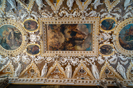 An elaborate ceiling adorned with frescoes, intricate gold detailing, and marble sculptures depicting mythological and allegorical figures in a historic palace.の写真素材