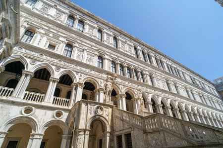 A grand Venetian architectural facade featuring intricate arches, statues, and detailed stonework under a clear blue sky.の写真素材