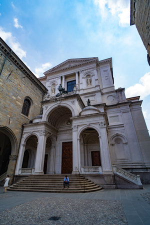 The majestic facade of Bergamo Cathedral in Piazza Duomo, showcasing classical Renaissance architecture and ornate sculptures under a blue sky.の写真素材