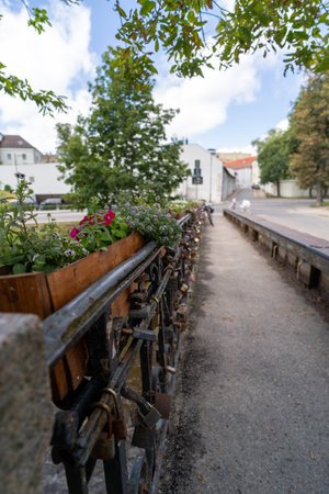 A charming wooden flower planter on a love lock bridge, with colorful blooms and a scenic pathway in the background.の写真素材