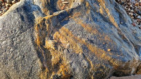 This image captures the natural orange veins and rugged texture of a coastal boulder in sunlight.の写真素材