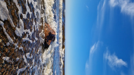 Rocky Shoreline Under Blue Sky and Dynamic Cloudsの写真素材