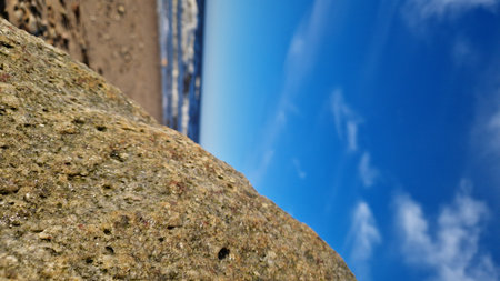 Coastal Boulder Overlooking Sunny Beachの写真素材