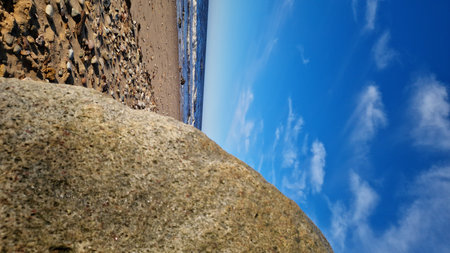 Boulder on Sandy Beach with Waves and Skyの写真素材