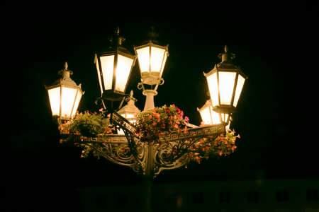 Six light street lantern decorated with flowers at night の写真素材