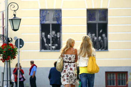 Student girls walking in university town Tartu  located in Estonia   On background photo-designed windows  teaching stuff welcomes everyone who passes nearby  のeditorial素材