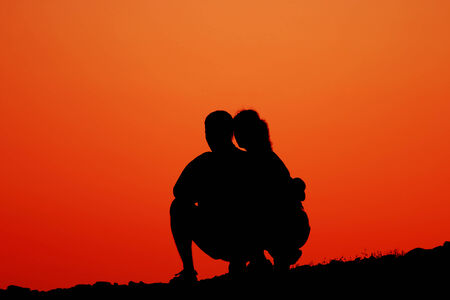 two young people looking at sundown on coastlineの写真素材