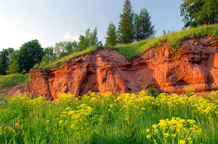 red color sandstone outcrop at meadow in summerの写真素材