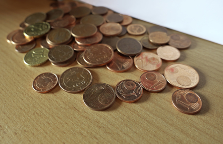 Euro coins of small value left on bookshelf (focus in foreground).の写真素材