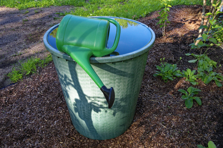 Watering barrel with watering can in garden.の写真素材