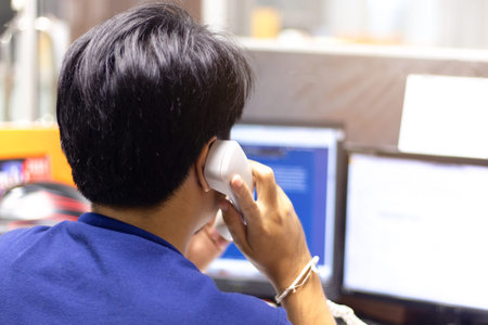 Closeup of businessman turn-back making a phone call on landline telephone. Concept of customer...