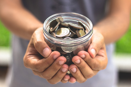 Hand holding glass jar with coins ,save money conceptの写真素材