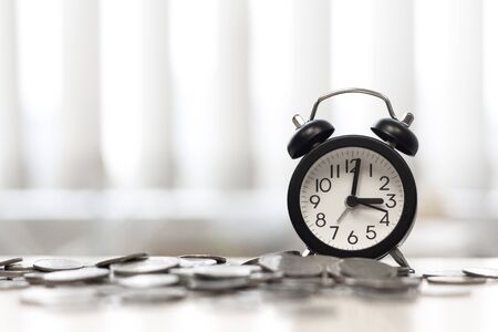 Clock and coins on desk table area window, Time is moneyの写真素材