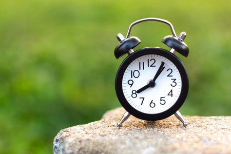 Clock on stone table in the green garden with copy space