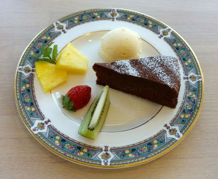 Chocolate cake dessert with strawberry, kiwi, pineapple and a scoop of vanilla ice creamの写真素材