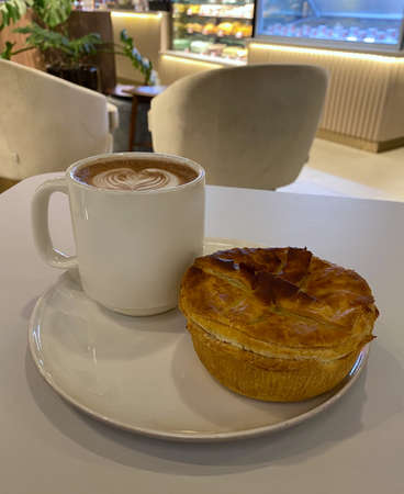 Freshly baked chicken mushroom pie and hot chocolate for breakfast. Warm toned led lighting inside a cafe.の写真素材