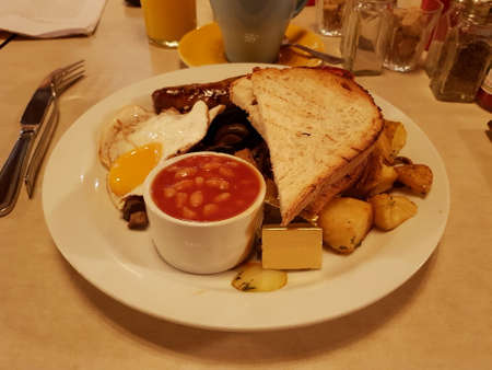 A full English breakfast includes bacon, sausage, egg, black pudding, baked bean, tomato, mushroom, toast bread and a cup of coffee. London, England, United Kingdom.の写真素材