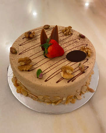 Creamy coffee flavoured cake decorated with almond flake, pistachio and walnut. Fresh strawberry and chocolate in the centre.の写真素材