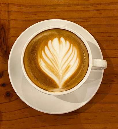 A cup of hot latte decorated with flower latte art.の写真素材