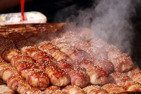 Steaming bread and bacon sprinkle with white sesame seeds. and steam up above the food on sunlight.の写真素材