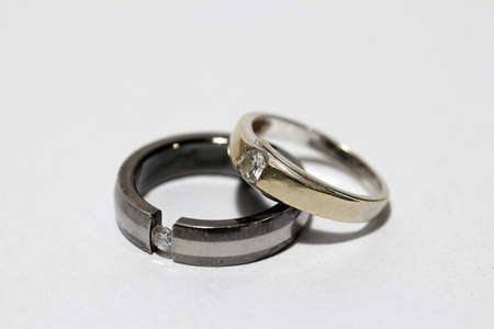 Two diamond rings stacked on white background. a small circular band, typically of precious metal and often set with one or more gemstones, worn on a finger as an ornament or a token of marriage, engagement, or authority.の写真素材