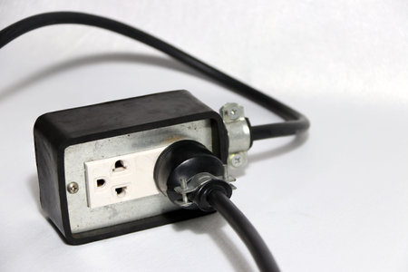 Plug in socket outlet with black cable on the white background. Used for electrical connection. Long...